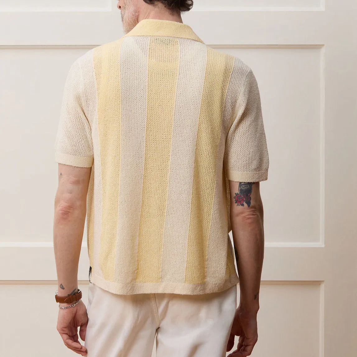 Yellow asymmetric short-sleeved polo shirt with hollow-out design on a hanger.
