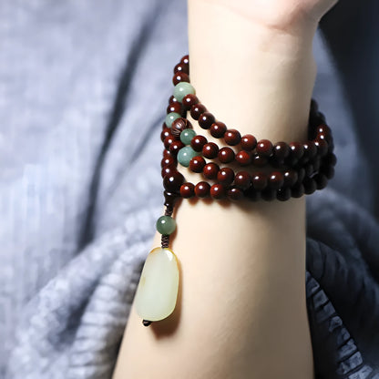 Rosewood bead bracelet with a carved wooden 108 bead and a green Hotian jade pendant on a neutral background.