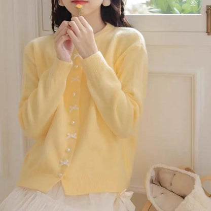 Women's solid colour cardigan sweater with bow pattern and pearl buttons in light blue.