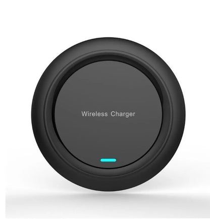 Round white wireless charging pad on desk next to mobile phone