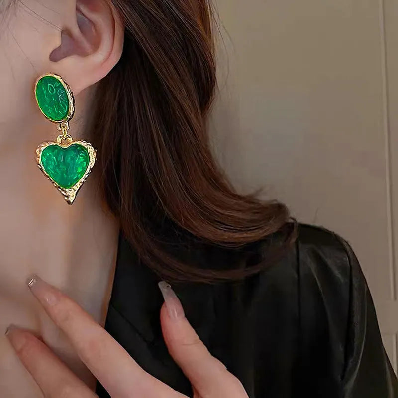 A pair of silver-tone stud earrings with a textured pleated oval love heart shape in various colour options.