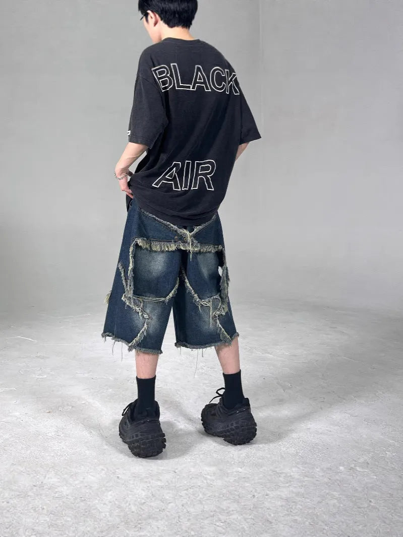 Blue men's loose-fit denim shorts with a frayed hem and a white five-pointed star patch on the leg.