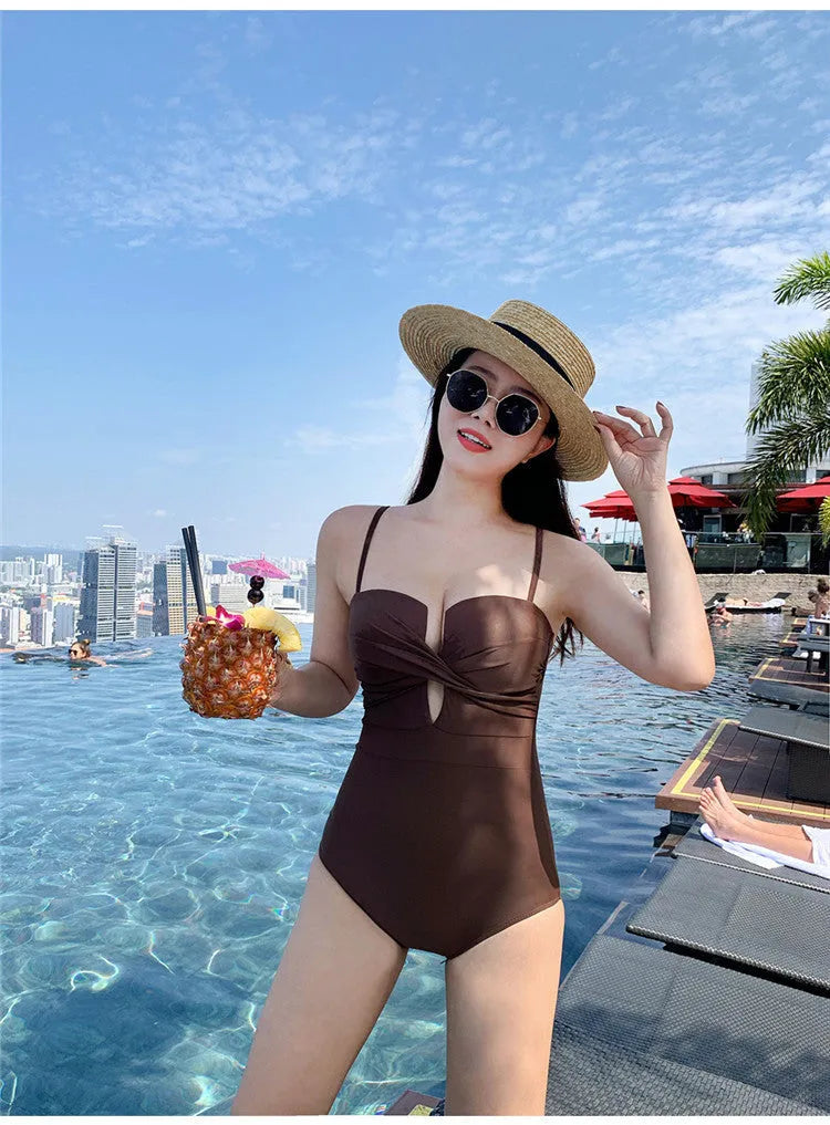 Women's solid colour one-piece swimsuit with spaghetti straps and push-up padding in white, pink, or brown options