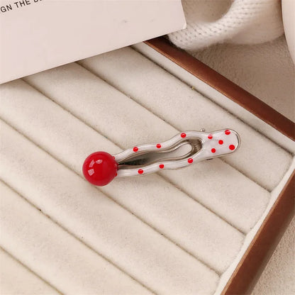 Red plastic hair clip with a 3D love heart and dots on a willow leaf-shaped base.