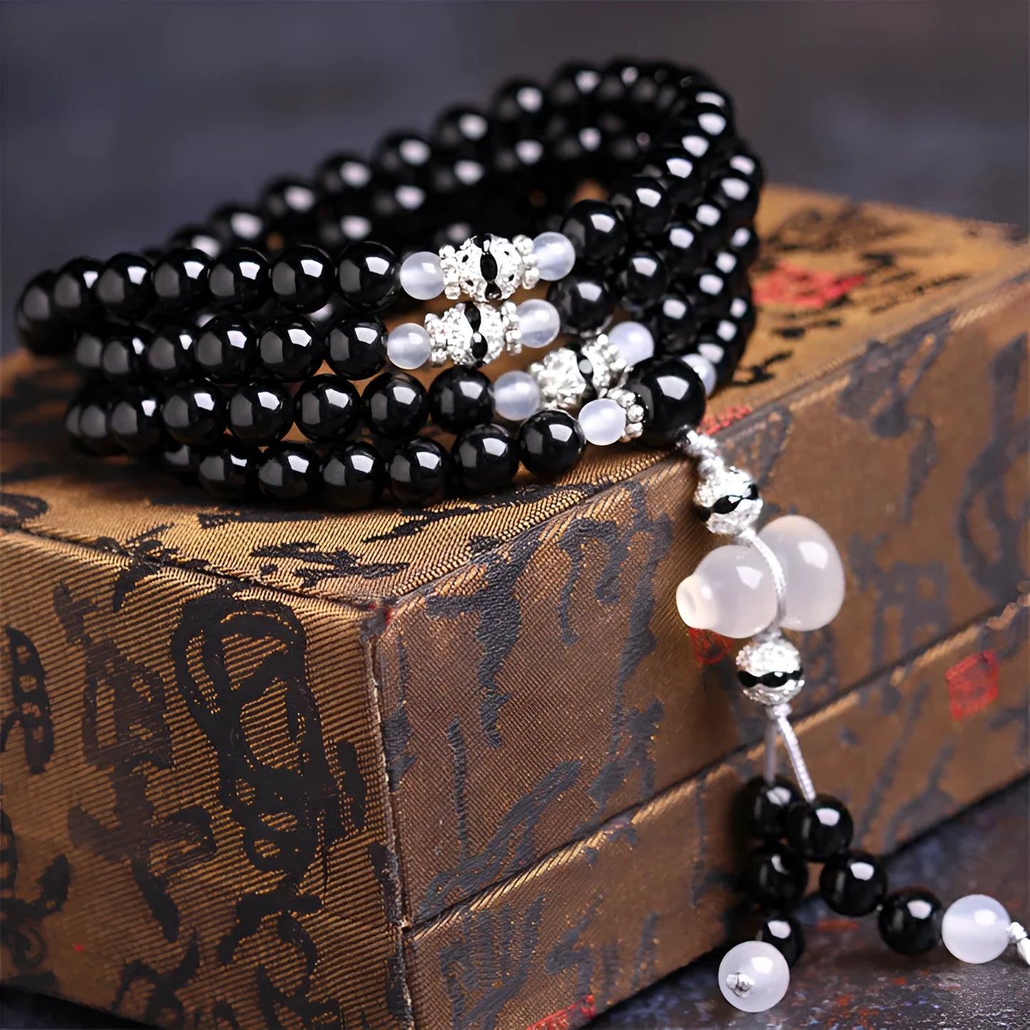 A bracelet made of 108 black geometric agate beads on a wrist.