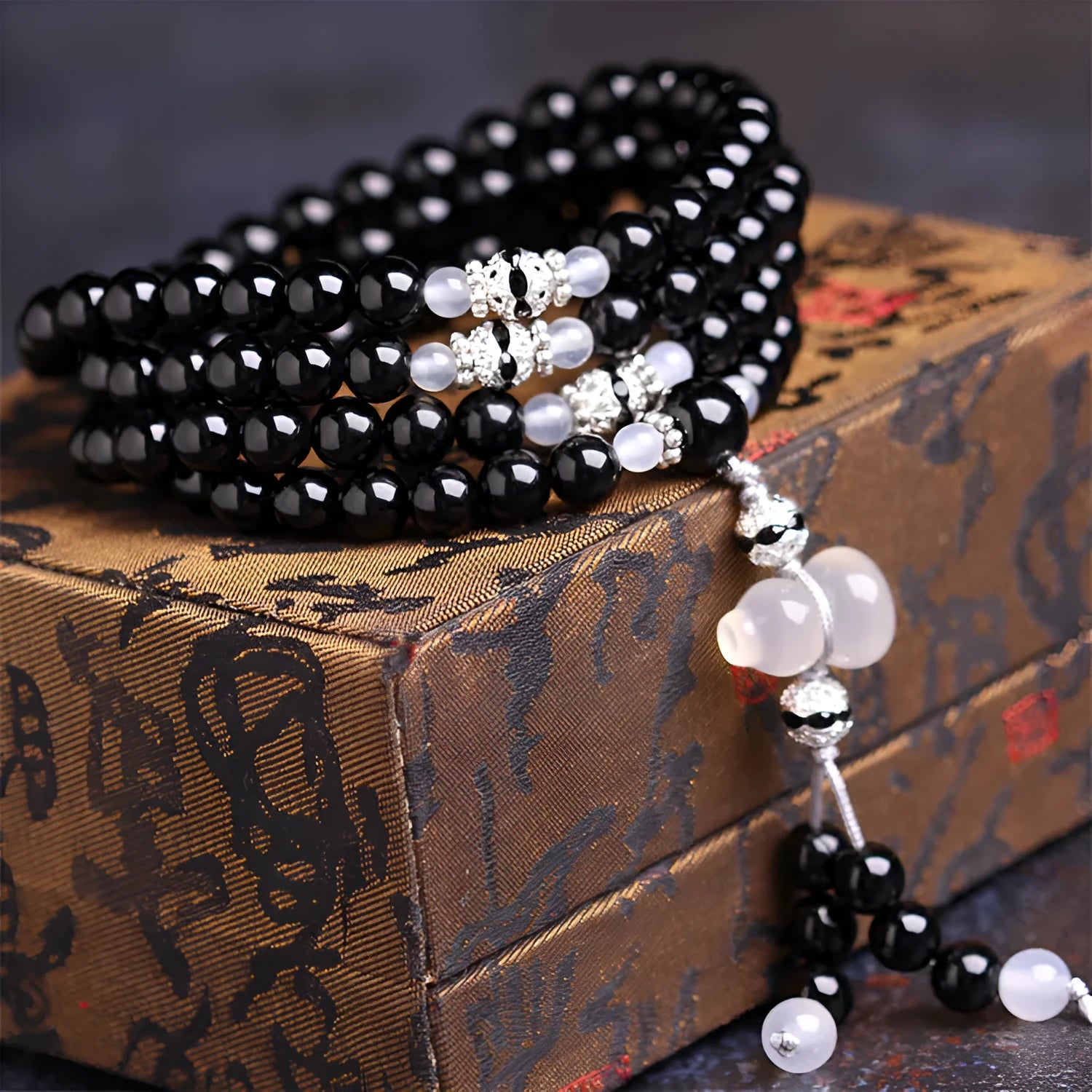 A bracelet made of 108 black geometric agate beads on a wrist.