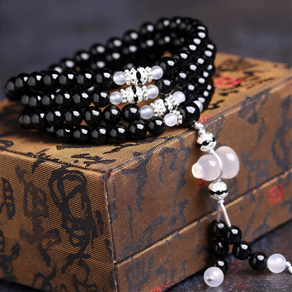 A bracelet made of 108 black geometric agate beads on a wrist.