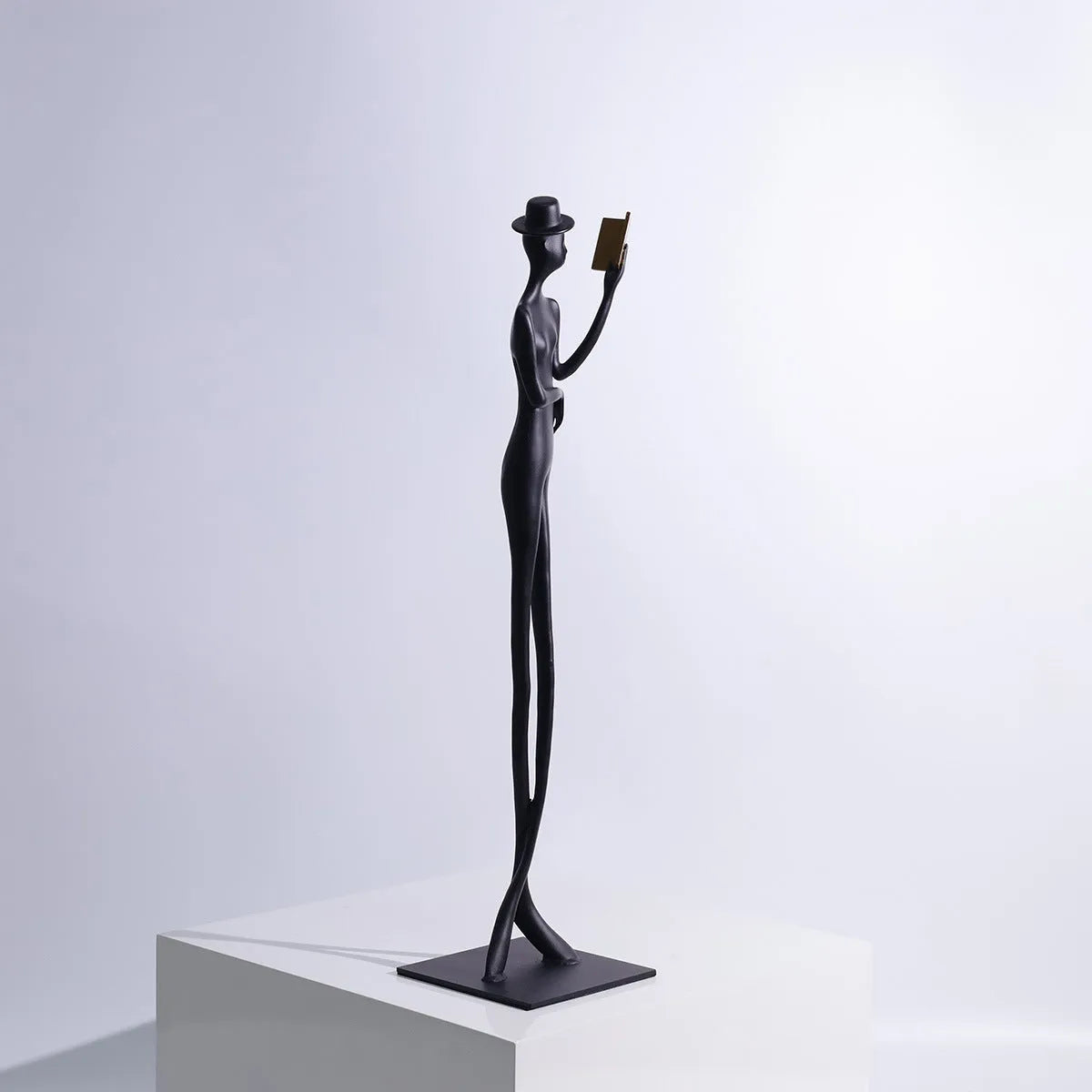 Black cast aluminium desktop sculpture of reading woman measuring 12x12x51cm with modern simplicity design