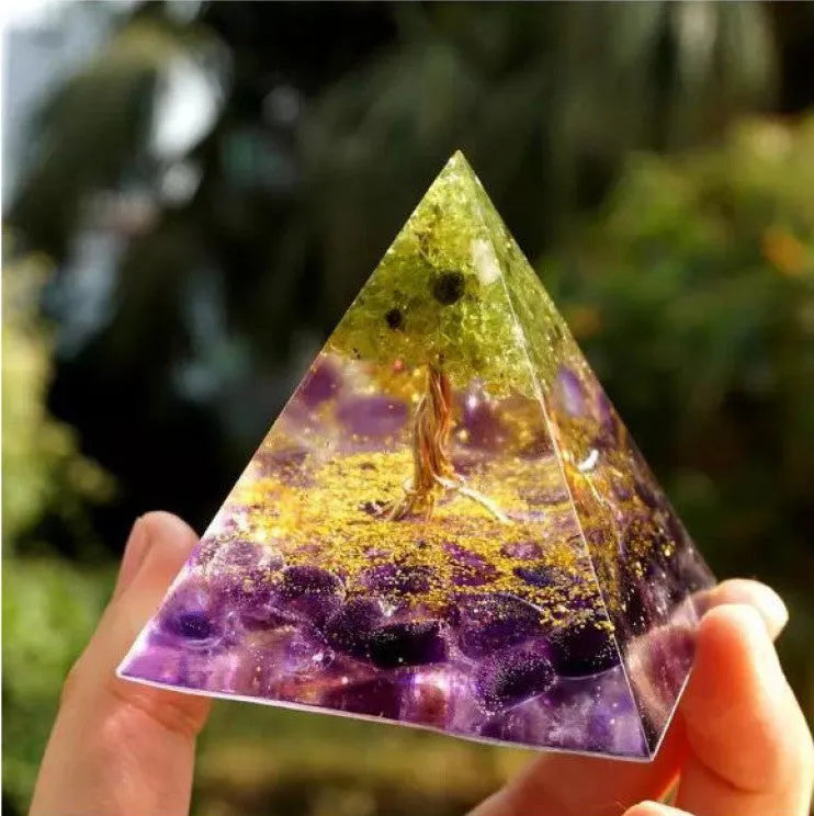 A small 6cm clear epoxy resin pyramid ornament containing pieces of natural crystal gravel on a flat surface.