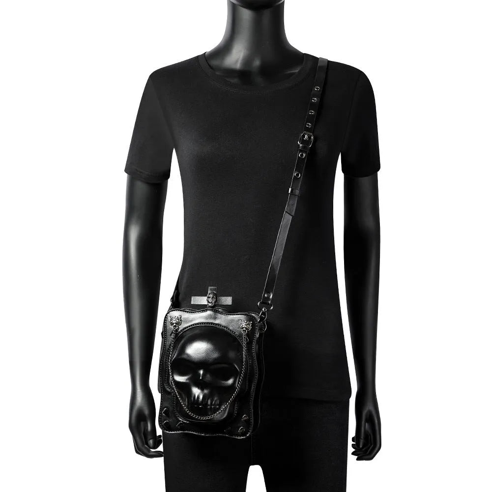 Black mini square messenger bag with embossed skull design, metal chains, and crossbody strap