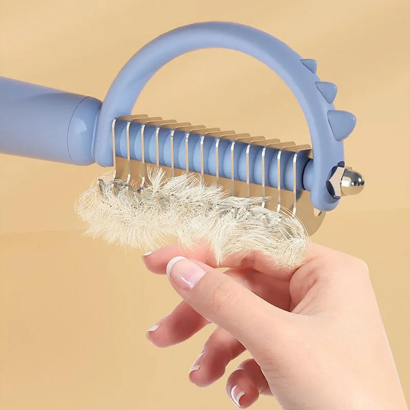 Blue dinosaur-shaped self-cleaning slicker brush for pet grooming on white background