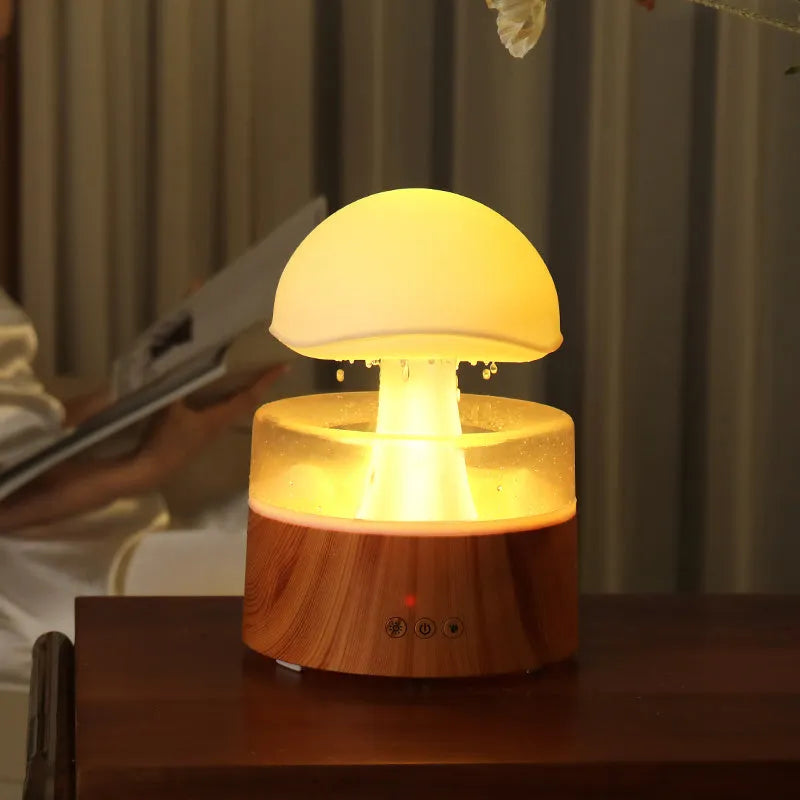 White rain cloud humidifier with falling water droplets and coloured LED lights on nightstand