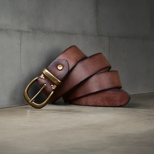 Men's black genuine cattlehide leather belt with a copper pin buckle on a jeans background.