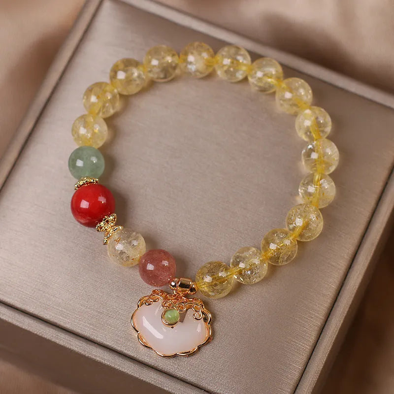 Women's yellow citrine jade ruyi pendant bracelet on wrist, alloy construction.