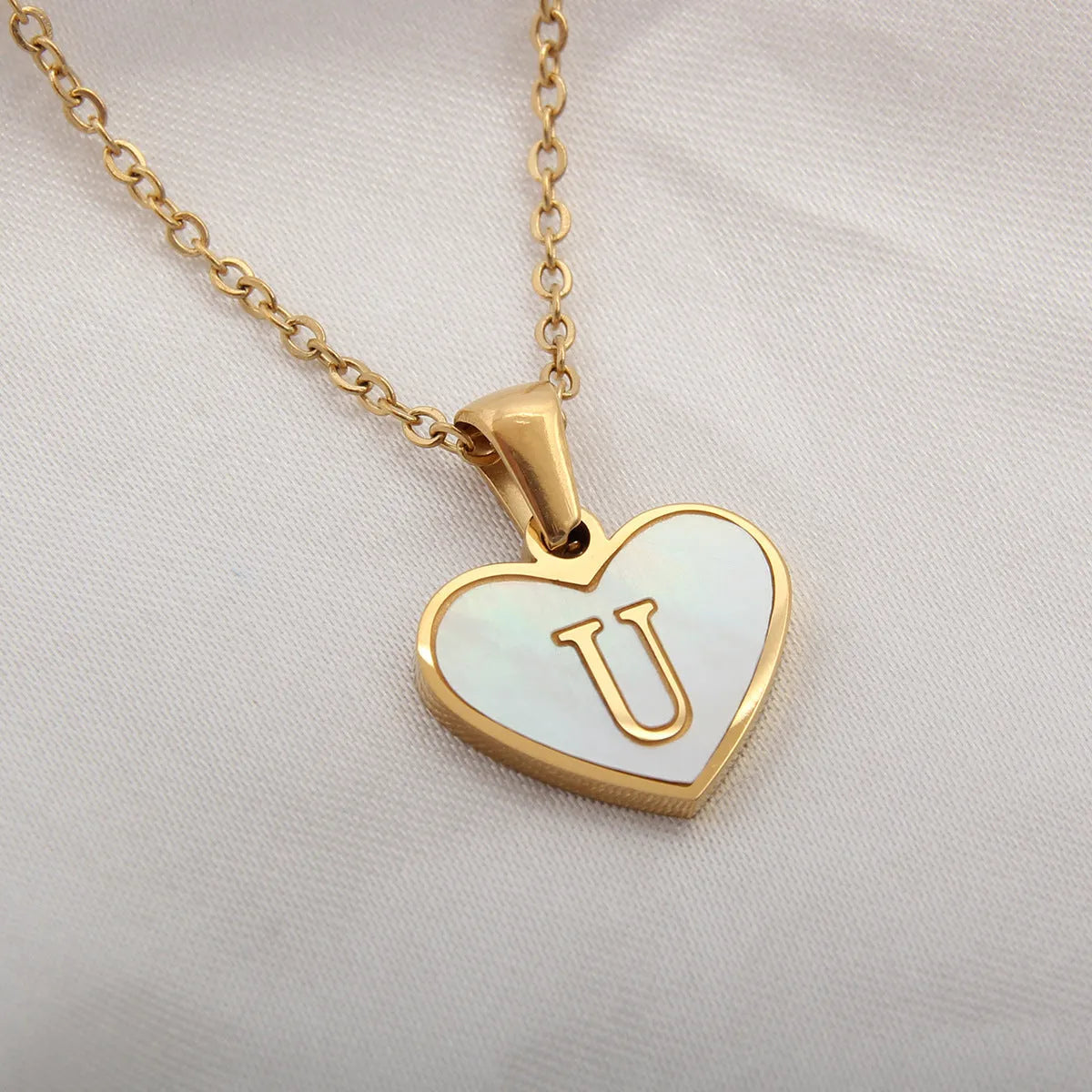Gold-plated clavicle necklace with a white shell heart pendant, personalised with a letter from A to Z.