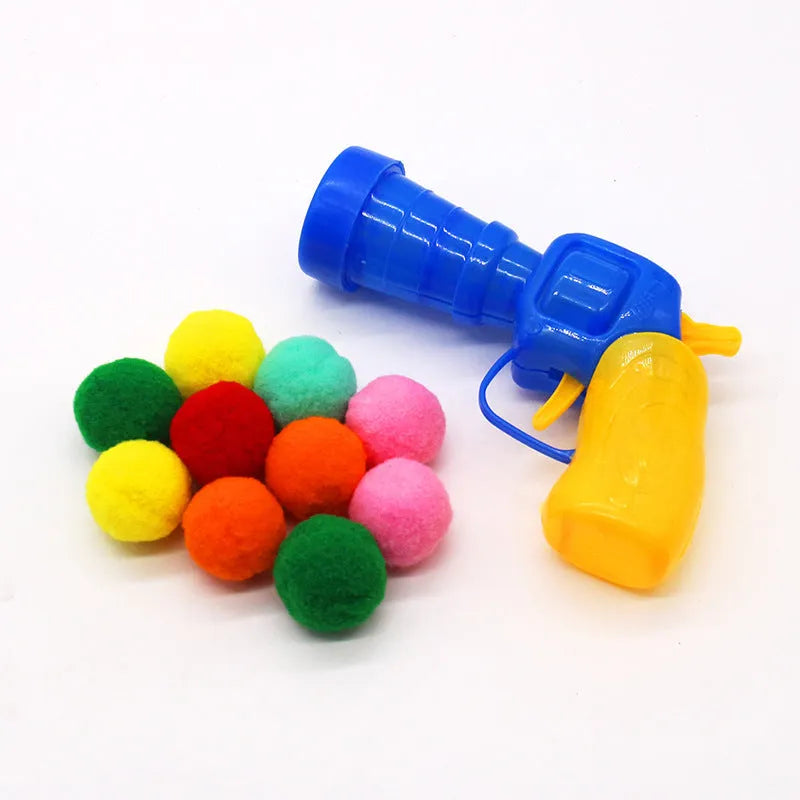 Interactive plastic pet toy gun and soft plush yarn balls on a carpet for fetch games.