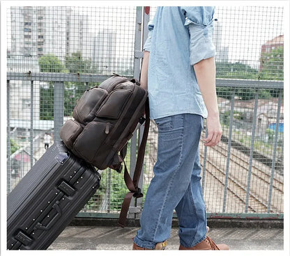 Dark brown leather backpack with embossed texture, double shoulder straps, and multiple zippered compartments for 17-inch laptops