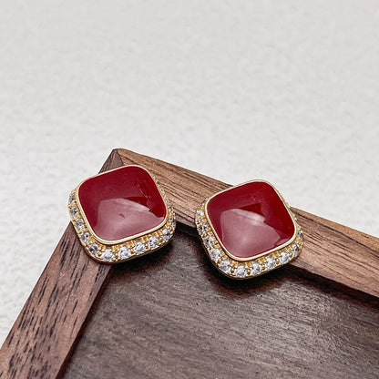 Red square alloy earrings with an inlaid geometric design, shown from the front.