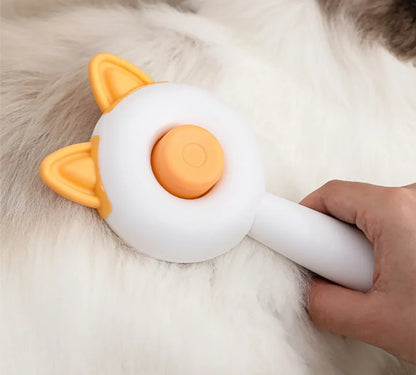 Greenish white pet grooming brush with stainless steel teeth, a push-button, and orange massage beads on the handle.