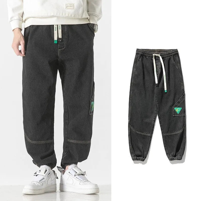 Men's loose-fit tapered cotton trousers in black showing mid-waist design and tapered leg opening