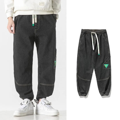 Men's loose-fit tapered cotton trousers in black showing mid-waist design and tapered leg opening