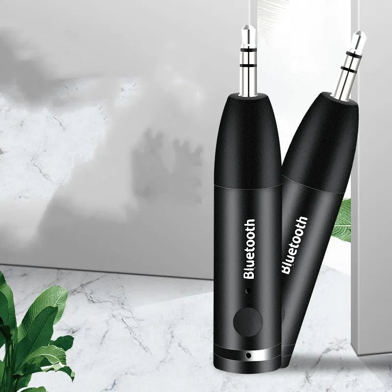 Compact black Bluetooth audio receiver with 3.5mm jack for car stereo and USB cable.