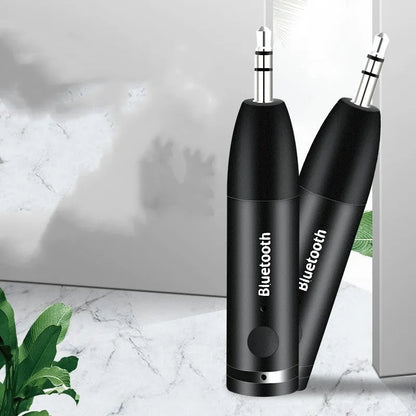 Compact black Bluetooth audio receiver with 3.5mm jack for car stereo and USB cable.