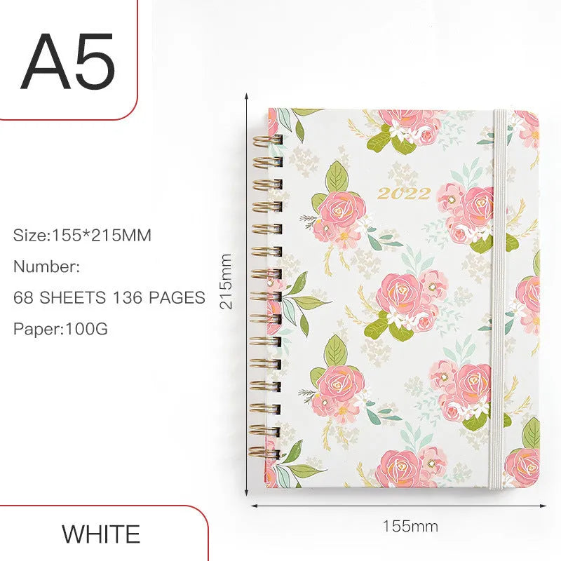 A5 spiral coil notebook open showing annual calendar pages and spiral binding