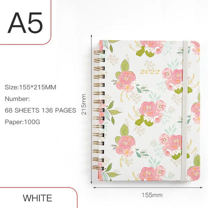 A5 spiral coil notebook open showing annual calendar pages and spiral binding
