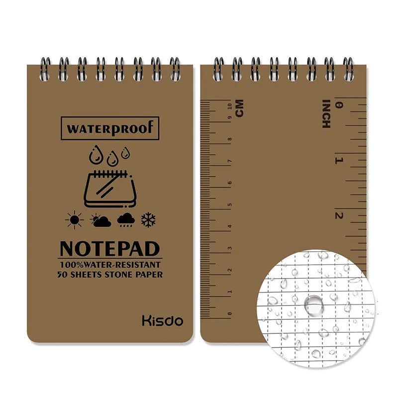 Spiral-bound waterproof notepad in camouflage colour, open on a desk with a pen, showing stone paper pages.
