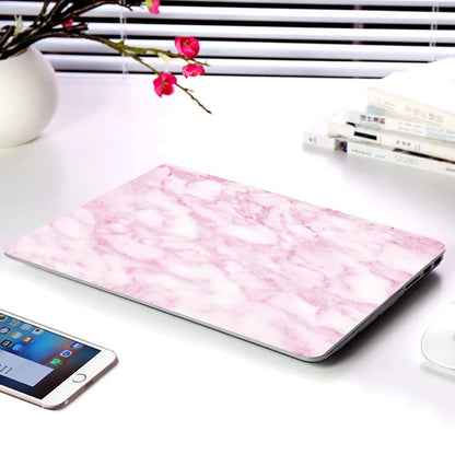 Plastic MacBook protective case in a marble pattern colour, shown next to a compatible Apple laptop.