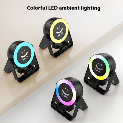Black and white wireless induction charging Bluetooth speaker with colourful LED lights on a desk.