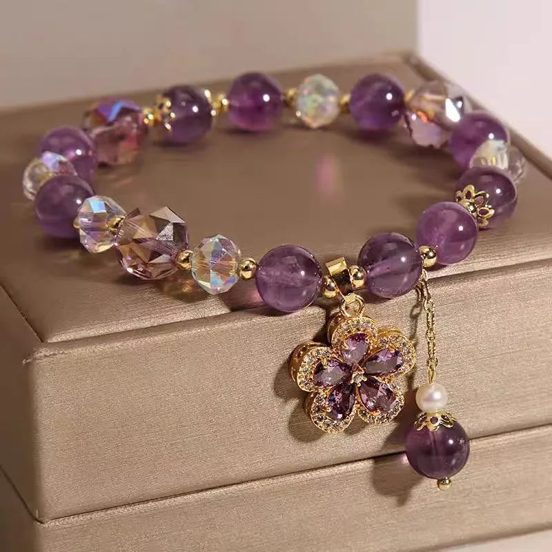 Natural purple amethyst crystal bracelet with nine-tailed fox and flower pendants on wrist.