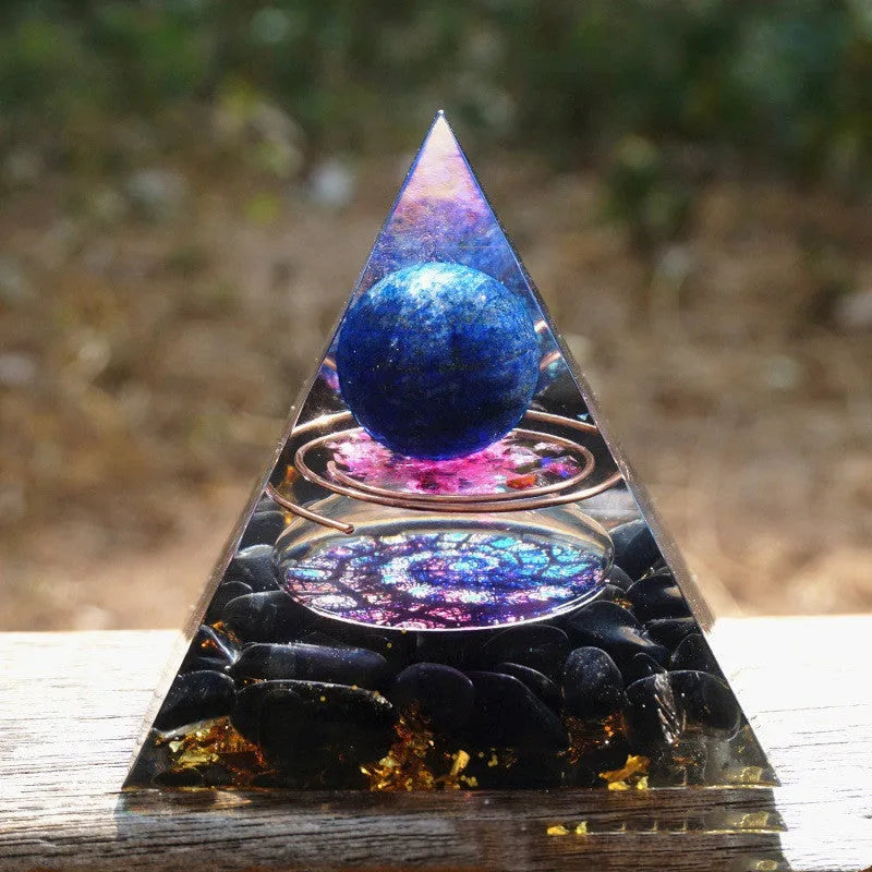 A small 6cm clear epoxy resin pyramid ornament containing pieces of natural crystal gravel on a flat surface.