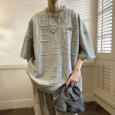 Grey men's loose T-shirt with a raised black three-dimensional retro letter design on the chest.