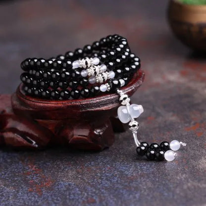 A bracelet made of 108 black geometric agate beads on a wrist.