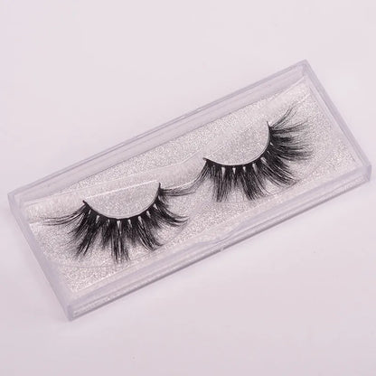 A pair of 5D mink false eyelashes with a hair storage cap and double-ended brush on a pink background.