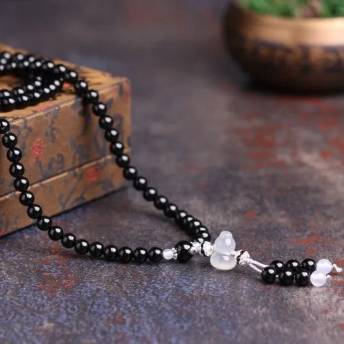 A bracelet made of 108 black geometric agate beads on a wrist.