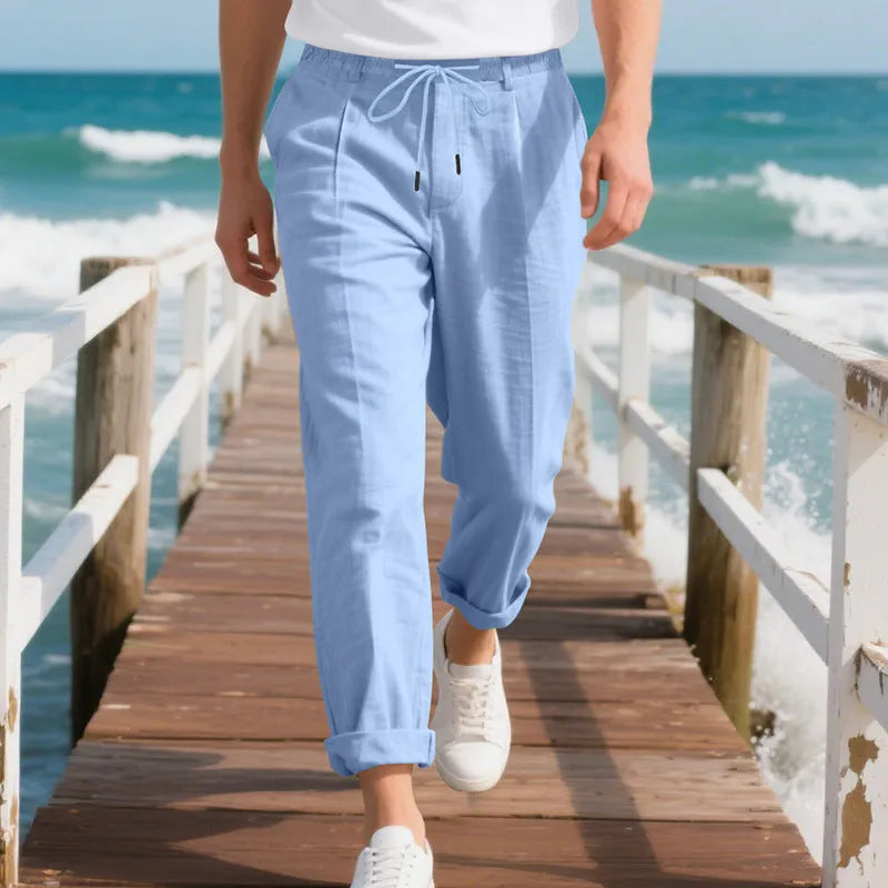 Men's light beige linen trousers with a loose straight leg and drawstring waist on a hanger.