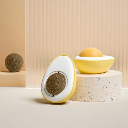 Interactive plush catnip ball toy shaped like a fried egg, stuck to a wall with a cat batting at it.