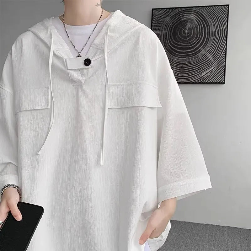 A man wearing a loose-fit black hooded short sleeve t-shirt for summer.