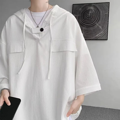 A man wearing a loose-fit black hooded short sleeve t-shirt for summer.