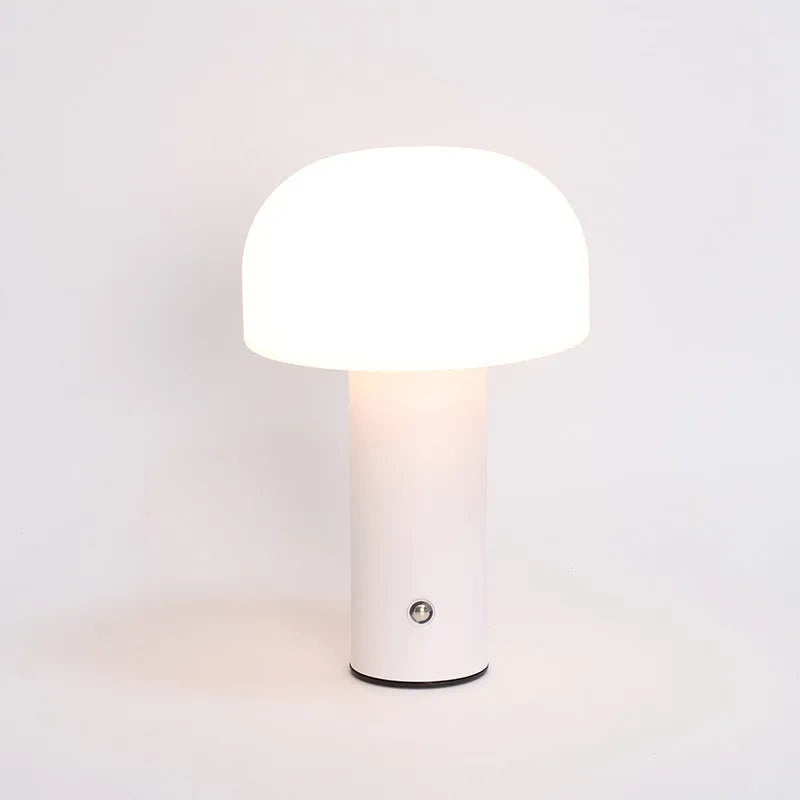 Compact white USB table lamp with integrated UK plug and a charging cable on a wooden desk.
