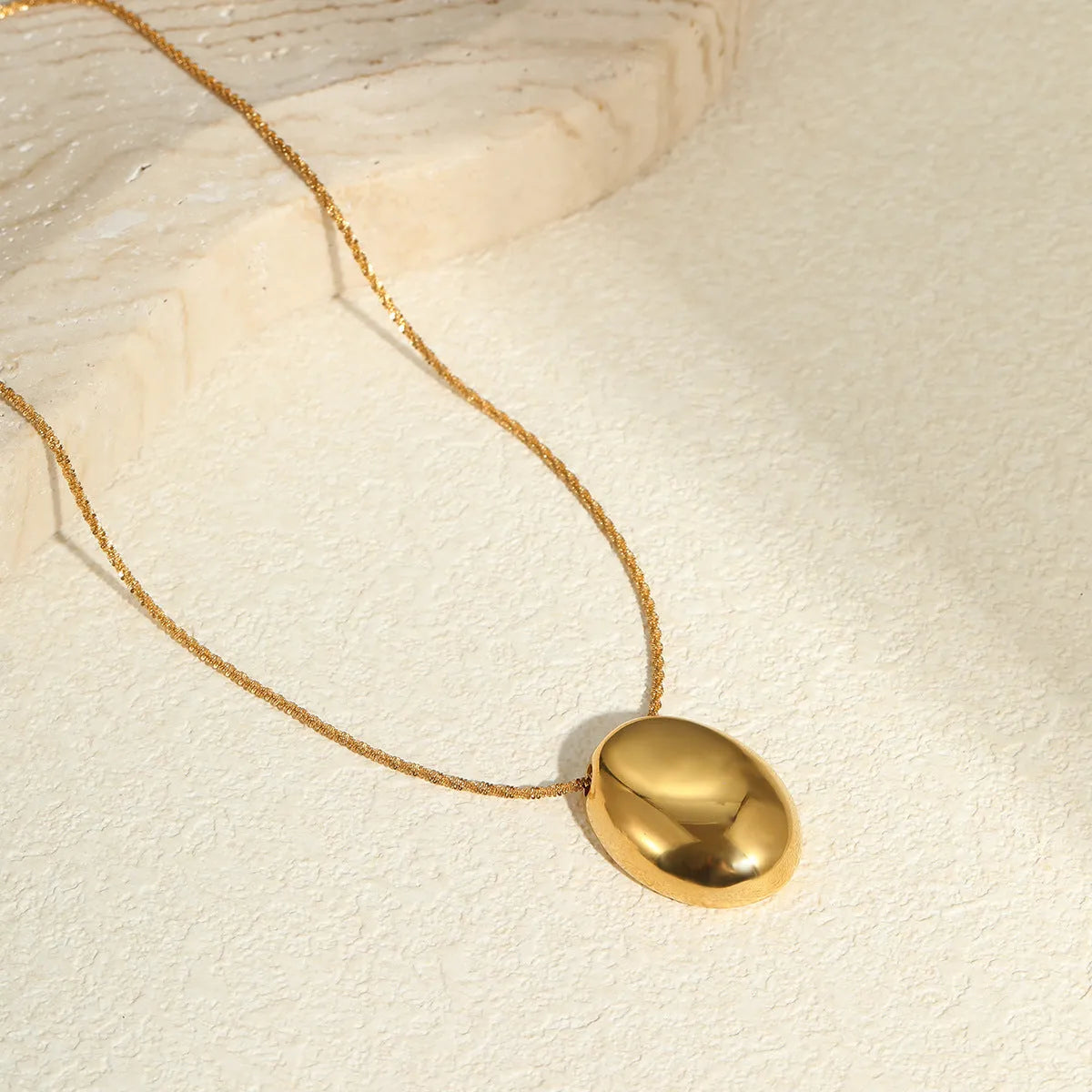 Gold-toned geometric pendant necklace on a chain, showing adjustable length between 41 cm and 50 cm.