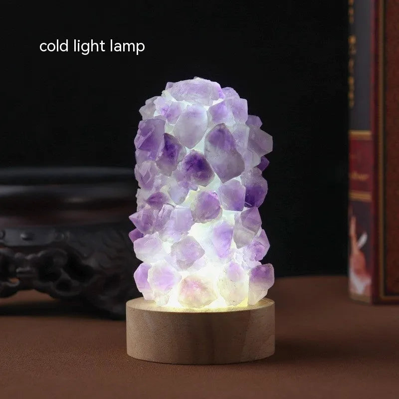 Miniature amethyst crystal tooth flower night light glowing with warm light on a wooden surface.