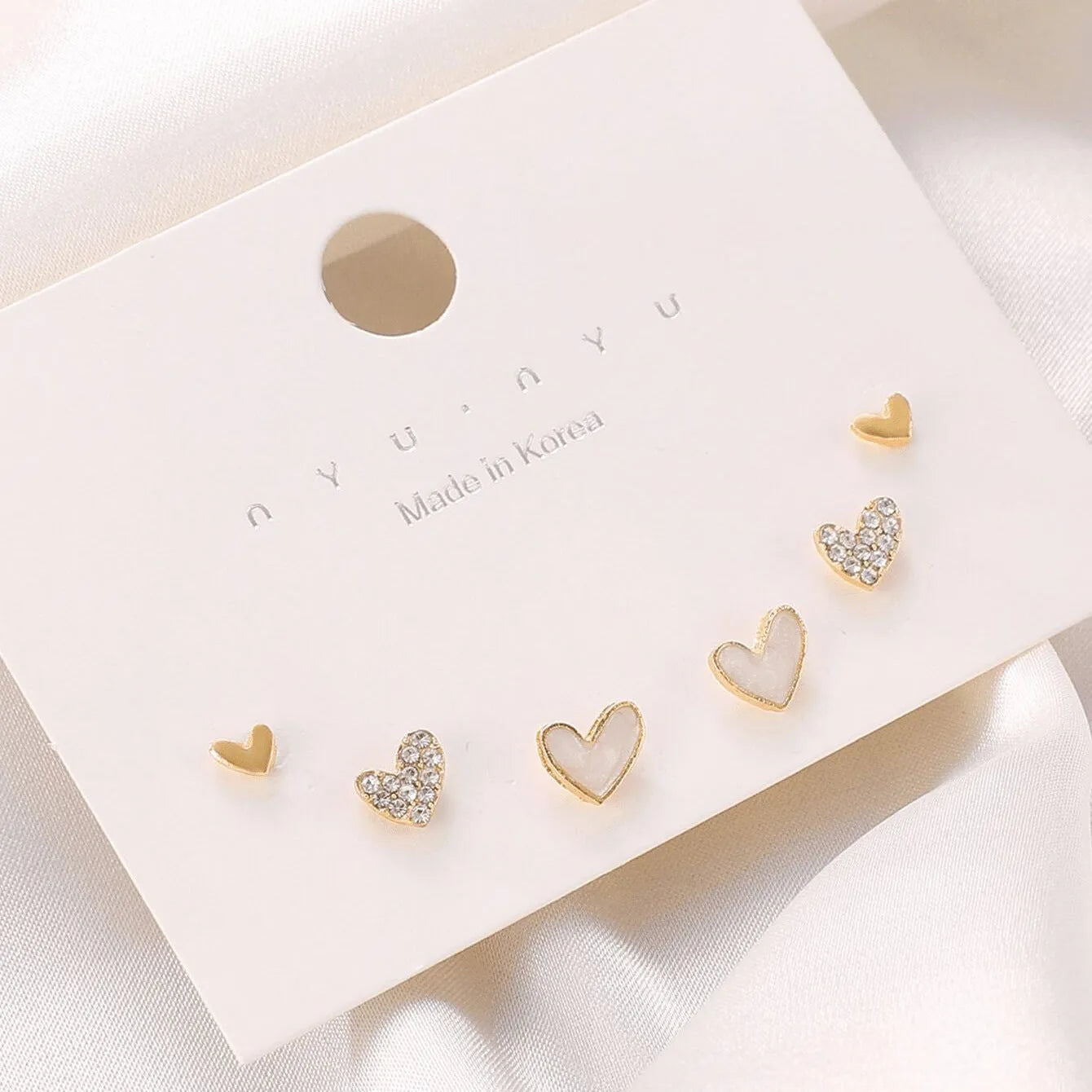 Three pairs of heart-shaped electroplated earrings in gold, black, black and white, and pink colours