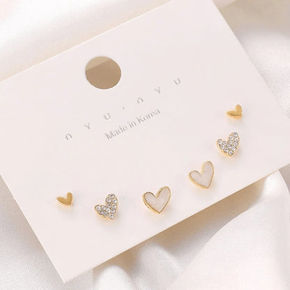 Three pairs of heart-shaped electroplated earrings in gold, black, black and white, and pink colours
