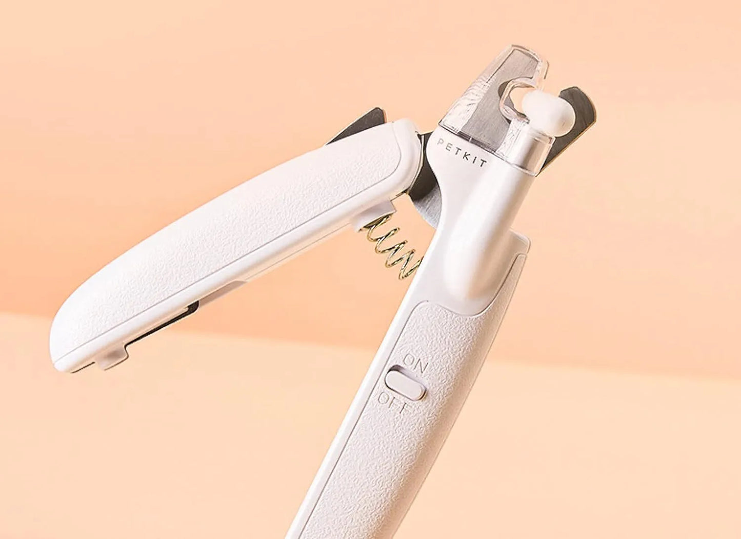 White pet nail clippers with LED light, anti-splash guard, and built-in nail file on a flat surface.