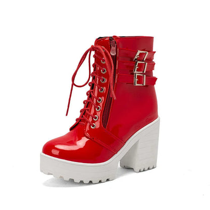 Women's black chunky heel ankle boots with round toe and front lace-up design on a wooden floor.