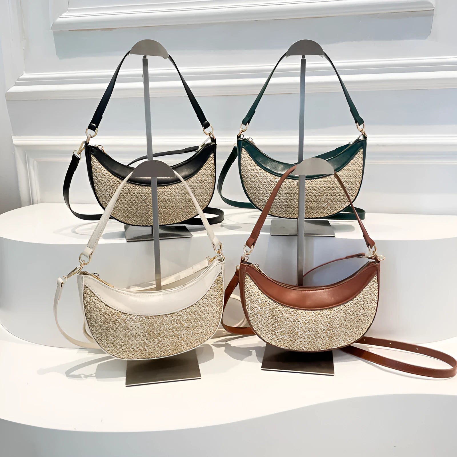 Women's hard-shell straw shoulder bag in a dumpling shape with a crossbody strap, shown in a choice of colours.